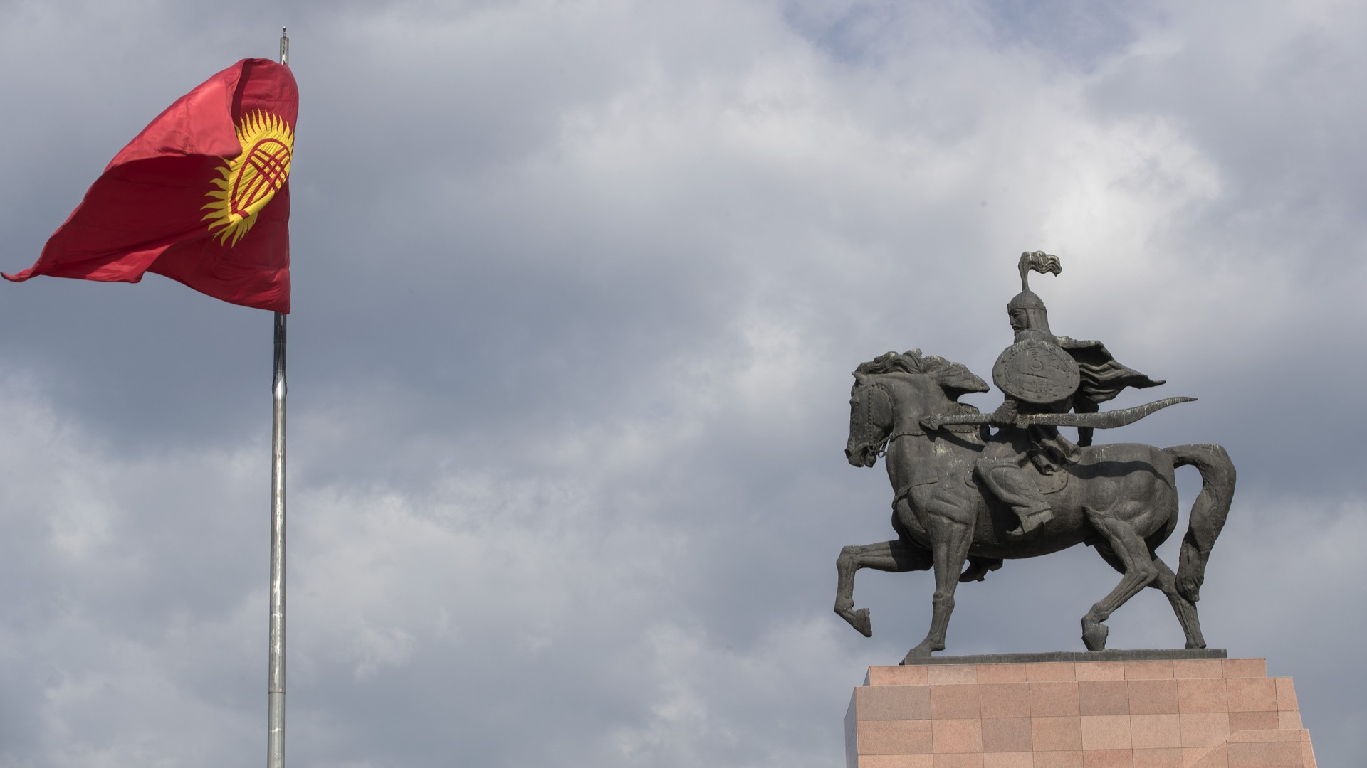 Флаг Кыргызстана и статуя Манаса на площади Ала-Тоо в Бишкеке.