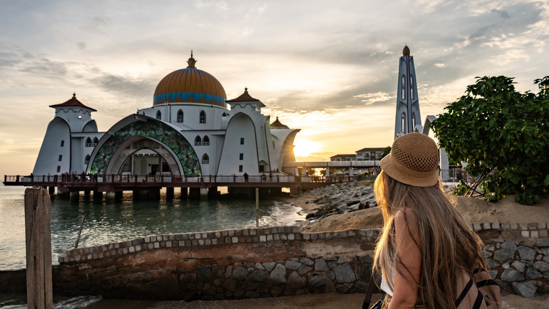 Женщина восхищается мечетью Малакки на закате в Малайзии.